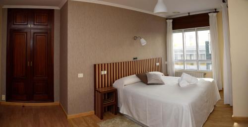 um quarto com uma cama com lençóis brancos e uma janela em Hotel Villa De Ribadeo em Ribadeo