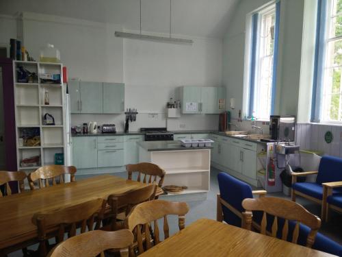 a kitchen with wooden tables and chairs and a kitchen with white cabinets at The Smugglers Hostel in Tomintoul