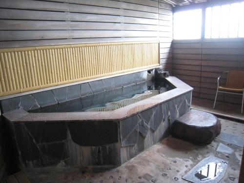 a large bath tub in a room with a chair at Mamesentaigetsu in Minamichita