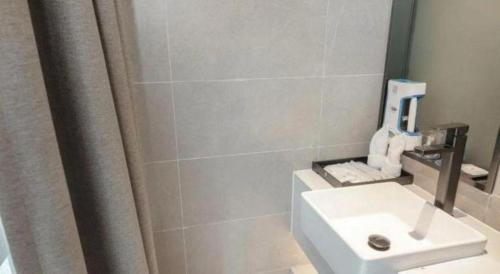 a bathroom with a white sink and a shower at H Life Hotel Nanshan Branch in Shenzhen