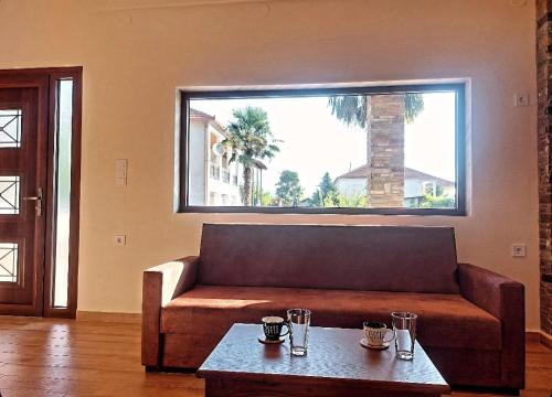 a living room with a couch and a large window at Petroula Suites Pozar in Kato Loutraki
