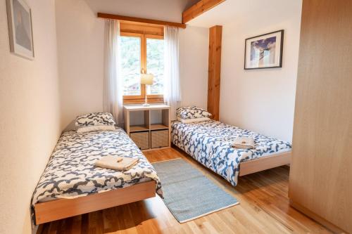 two beds in a small room with a window at St Martin Loft Apartment in Täsch