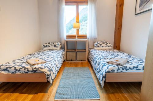 two beds in a small room with a window at St Martin Loft Apartment in Täsch