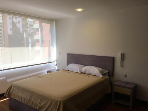1 dormitorio con 1 cama grande y ventana en Apartamento Finlandia Park Suite, en Quito