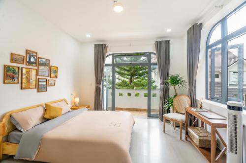 a bedroom with a bed and a desk and a window at Homey Villa in Da Lat