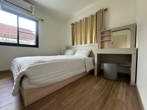 Un dormitorio con una cama, un escritorio y un espejo. en 2BR New renovation house in Phitsanulok, en Ban Khlong