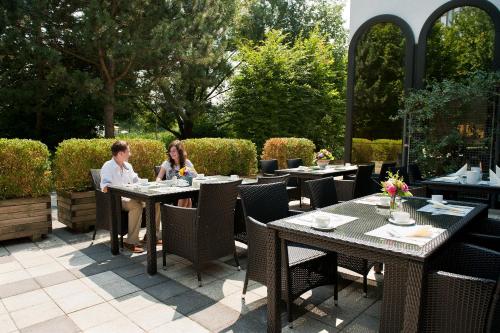two people sitting at tables on a patio at Atrium im Park Hotel Regensburg in Regensburg