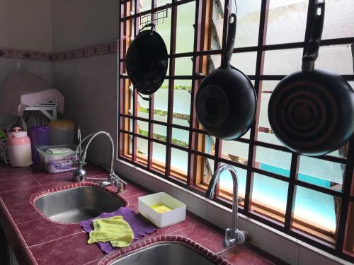 a kitchen sink with pots and pans hanging from a window at Seri Pengkalan Guest House in Bachok