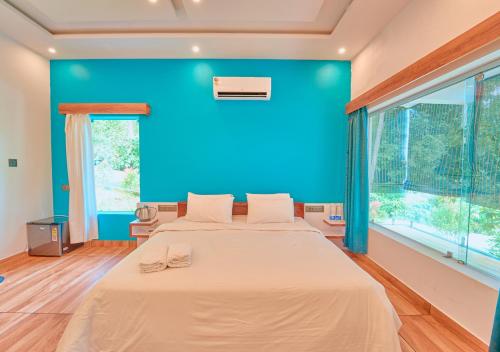 a bedroom with a blue wall and a large bed at Maryland Nature Stay Wayanad by VOYE HOMES in Wayanad