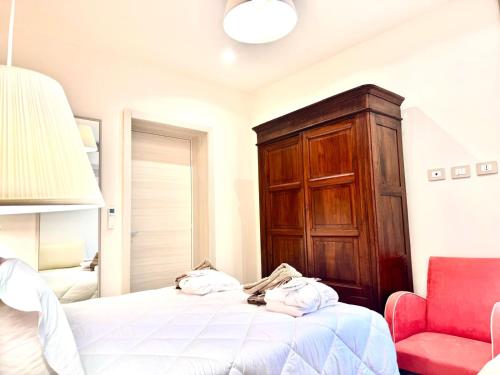 a bedroom with a bed with a wooden cabinet and a red chair at Hotel Astigiana & Appartamenti in Varazze