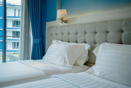 a bed with white sheets and pillows next to a window at BlueSotel Krabi AoNang Beach in Ao Nang Beach