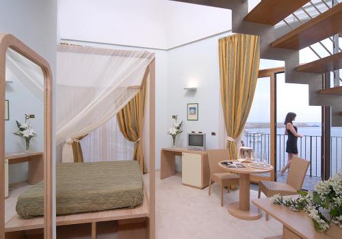 una mujer parada en un dormitorio con una cama y una mesa en Hotel Villa Carolina, en Isquia