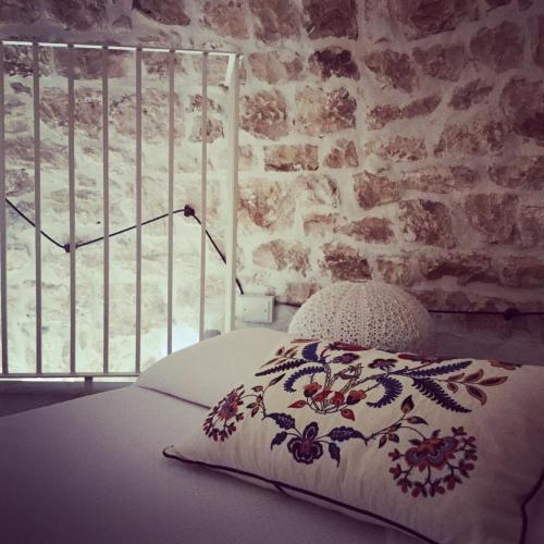 a bed with a patterned pillow next to a brick wall at Trullidea in Alberobello