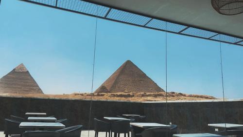 a view of the pyramids from a restaurant with tables and chairs at Comfort Sphinx & Pyramids Inn in Cairo