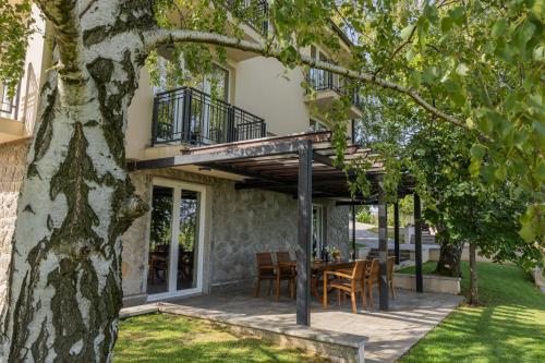 a house with a deck and a table and chairs at Vikendica Aleksandrović Meterize in Topola