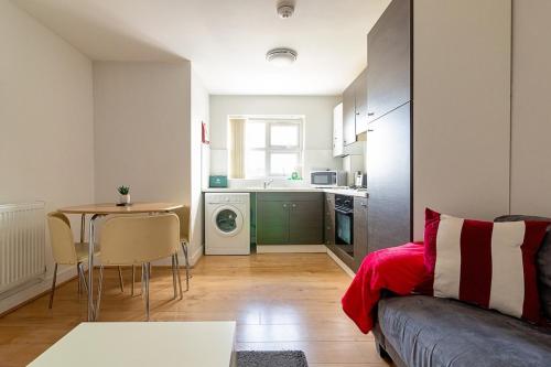 a living room with a couch and a table and a kitchen at 2nd Floor Town Centre Apt with FREE Parking in Loughborough