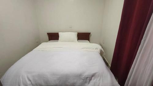 a white bed in a small room with curtains at Apartment in Kigali