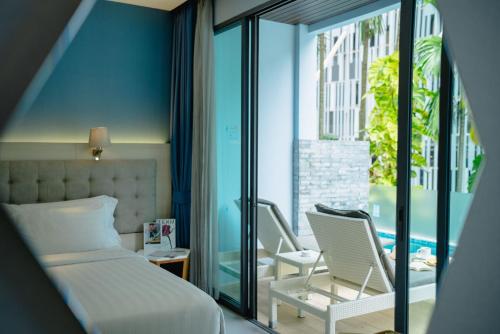 a bedroom with a bed and two chairs on a balcony at BlueSotel Krabi AoNang Beach in Ao Nang Beach