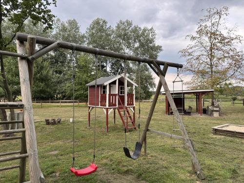 a playground with a swing set and a house at Blockhäuser auf Reiterhof in Eschede in Eschede