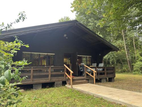 a black cabin with a porch in the woods at Blockhäuser auf Reiterhof in Eschede in Eschede