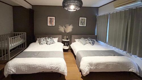 a bedroom with two beds and a crib at YURURIBASE 凛 in Nagahama contactless checkin in Nagahama