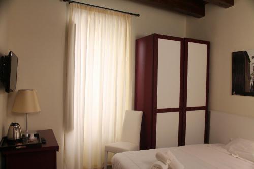 1 dormitorio con 1 cama, 1 silla y 1 ventana en Il Borgo Ospitale - Albergo Diffuso, en Rotonda