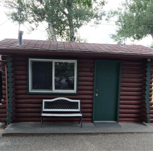 a bench sitting outside of a log cabin with a green door at Z Bar Motel in Buffalo