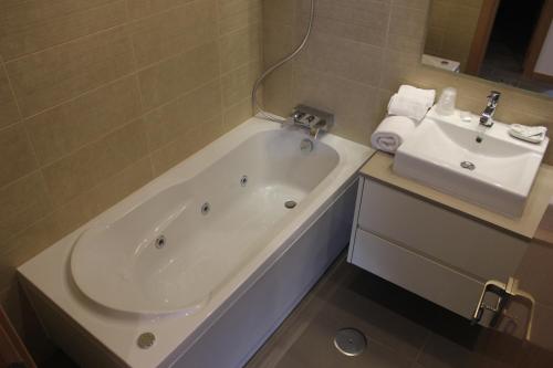 uma casa de banho com uma banheira e um lavatório em Apartamentos Turisticos da Nazare na Nazaré
