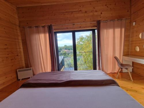 a bedroom with a bed and a large window at NEO resort Hill jezero Bruje in Erdevik