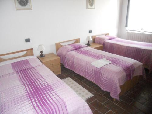 three beds in a room with pink sheets at Tenuta Il Tresto in Poggibonsi