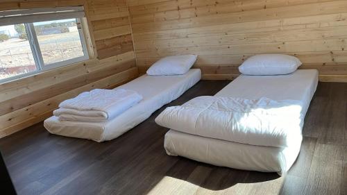 two beds in a room with a wooden wall at 057A Brand New Cozy Cabin with Loft & King bed near Grand Canyon South Rim in Valle