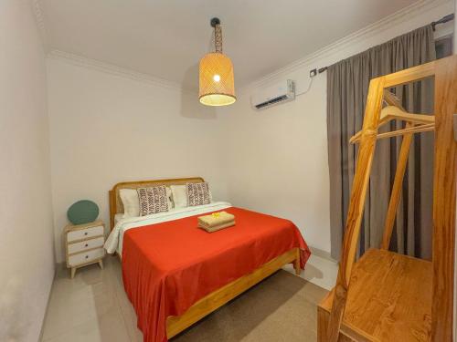 a bedroom with a bed with a orange blanket at Rumah Tetangga Jogja - 4BR Villa Near Keraton in Ngabean
