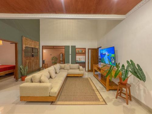 a living room with a couch and a flat screen tv at Rumah Tetangga Jogja - 4BR Villa Near Keraton in Ngabean