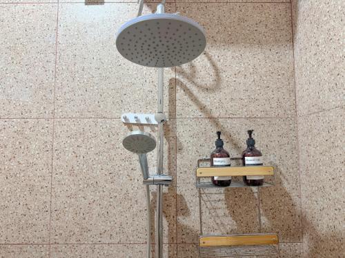 a shower in a bathroom with two bottles of alcohol at Rumah Tetangga Jogja - 4BR Villa Near Keraton in Ngabean