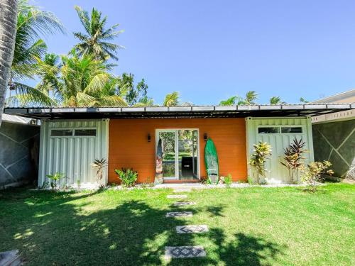 an orange house with a grass yard in front of it at Tropical 2BR Escape & Walk to Selong Belanak Beach in Selong Belanak