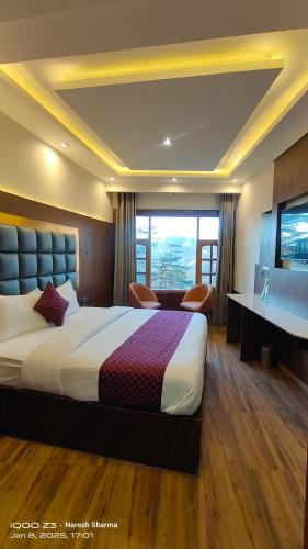 a bedroom with a bed and a desk and a television at Magic Stays Simla Royale - Near Mall Road Free Pickup from railway station Shiimla in Shimla