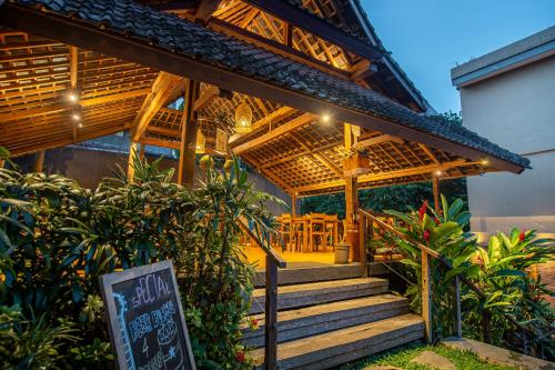 a restaurant with stairs and a sign in front of it at Merak Village by Prasi in Ubud
