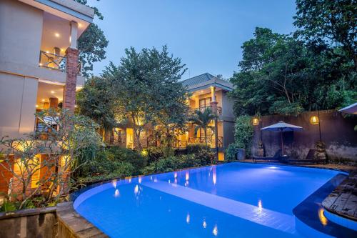 a swimming pool in front of a house at night at Merak Village by Prasi in Ubud