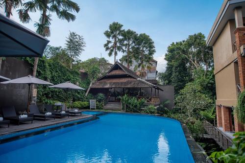a swimming pool in front of a house at Merak Village by Prasi in Ubud