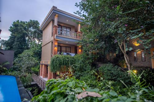 a house with a balcony and trees and bushes at Merak Village by Prasi in Ubud