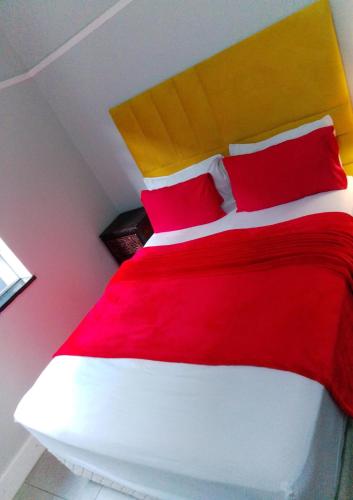 a bedroom with a red and white bed with red pillows at Neo & Ruks Guest Houses parow 4 in Avondale