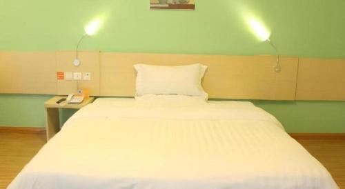a large white bed in a room with two lights at 7 Days Inn Guangrao Bus Station in Dongying