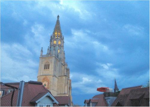 a church steeple with a clock tower in a city at Ferienwohnung ATELIER MÜNSTERBLICK in Konstanz