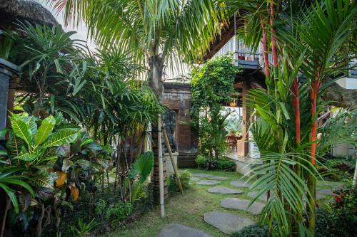 a garden with palm trees and a building at d'kamala by Prasi in Ubud