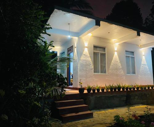 a white house with stairs in front of it at night at Ella Hidden Ferns in Ella