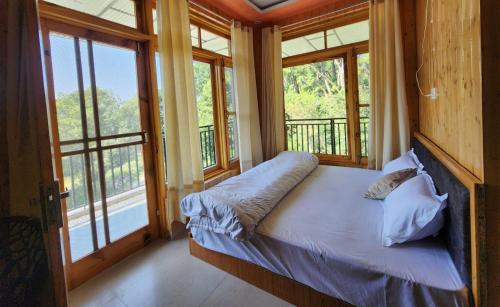 a bedroom with a bed in a room with windows at riverview villa in Bīr