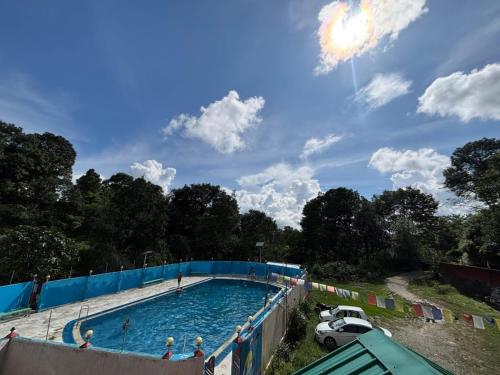 a large swimming pool with people in the water at riverview villa in Bīr
