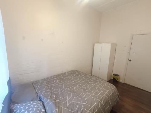 Un dormitorio pequeño con una cama y un refrigerador. en Affordable Queen Room in Earlwood - EW5, en Sídney