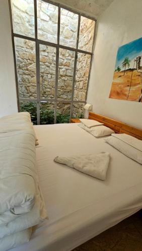 a bedroom with a large white bed with a window at Wadi Dana Lodge - نزل وادي ضانا in Dana