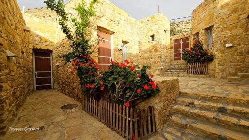 a stone building with flowers on a fence at Wadi Dana Lodge - نزل وادي ضانا in Dana
